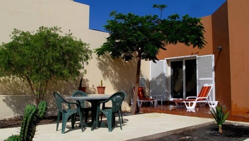 Casa con piscina entre jardines y finca de olivos.