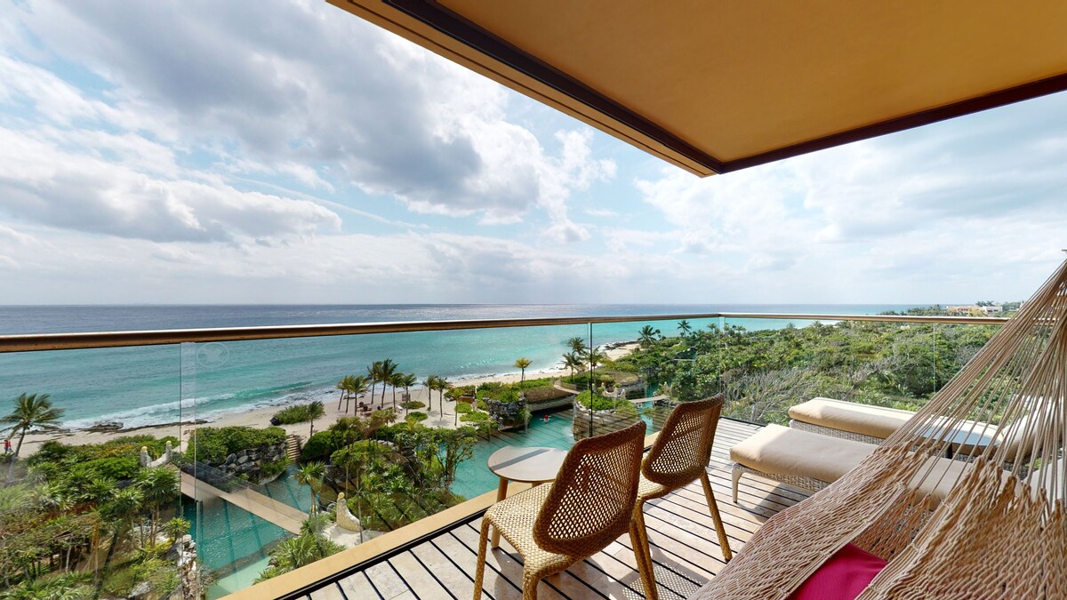Enjoy a tranquil ocean view from this resort's balcony, featuring a hammock and wicker furniture.