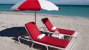 Am Strand, weißer Sandstrand, Liegestühle, Sonnenschirme