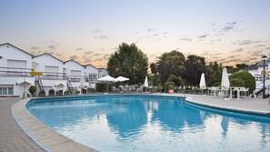 Una piscina al aire libre de temporada, sombrillas, tumbonas