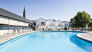 Una piscina al aire libre de temporada, sombrillas, tumbonas