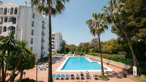 Una piscina al aire libre de temporada, sombrillas, tumbonas
