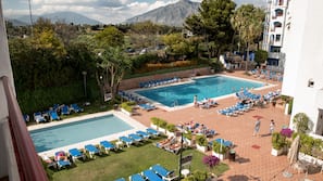 Una piscina al aire libre de temporada, sombrillas, tumbonas