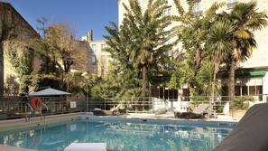 Una piscina al aire libre, sombrillas, tumbonas