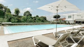 Una piscina al aire libre de temporada, sombrillas, tumbonas