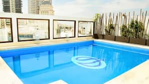 Una piscina al aire libre de temporada, sombrillas, tumbonas