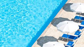 Una piscina al aire libre de temporada, sombrillas, tumbonas