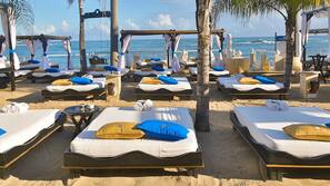 Aan het strand, wit zand, ligstoelen aan het strand, parasols