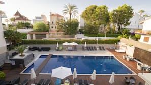 Una piscina al aire libre de temporada, sombrillas, tumbonas