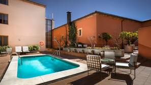 Una piscina al aire libre de temporada, tumbonas