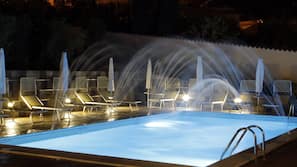 Una piscina al aire libre de temporada, sombrillas