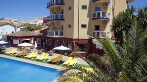 Una piscina al aire libre, sombrillas, tumbonas