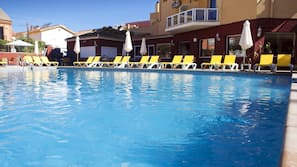 Una piscina al aire libre, sombrillas, tumbonas