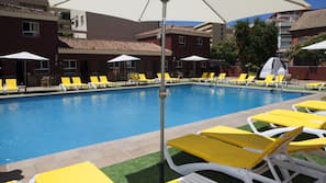 Una piscina al aire libre, sombrillas, tumbonas
