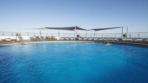 Una piscina al aire libre, tumbonas