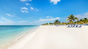 Na praia, areia branca, espreguiçadeiras, toalhas de praia