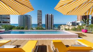 Una piscina al aire libre, sombrillas, tumbonas