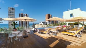 Una piscina al aire libre, sombrillas, tumbonas