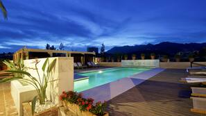 Una piscina al aire libre, sombrillas, tumbonas