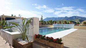 Una piscina al aire libre, sombrillas, tumbonas