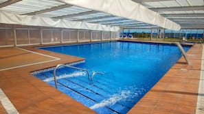 Una piscina cubierta, una piscina al aire libre, tumbonas