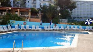 Una piscina al aire libre, tumbonas