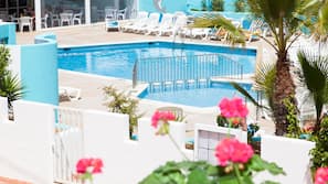 Una piscina al aire libre, tumbonas