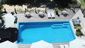 Una piscina al aire libre, sombrillas, tumbonas