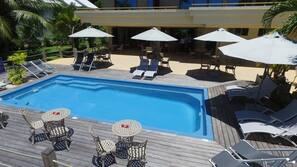 Una piscina al aire libre, sombrillas, tumbonas