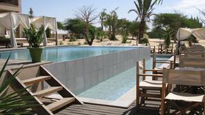 Una piscina al aire libre, sombrillas, tumbonas