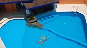 Una piscina al aire libre, sombrillas, tumbonas