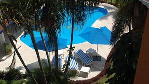 Una piscina al aire libre, sombrillas, tumbonas