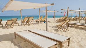 On the beach, white sand, sun loungers, beach towels
