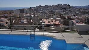 Una piscina al aire libre, sombrillas, tumbonas