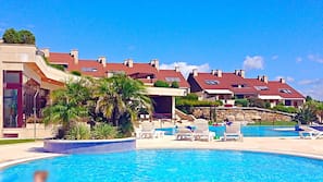 Una piscina cubierta, una piscina al aire libre, tumbonas
