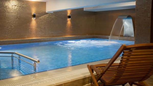 Una piscina cubierta, una piscina al aire libre, tumbonas