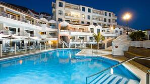 Una piscina al aire libre, sombrillas, tumbonas