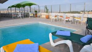 Una piscina al aire libre, sombrillas, tumbonas