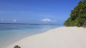 Am Strand, weißer Sandstrand, Liegestühle, Sonnenschirme