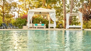 Una piscina al aire libre, sombrillas, tumbonas