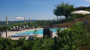 Una piscina al aire libre de temporada, sombrillas, tumbonas