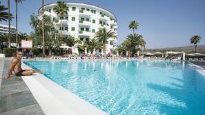 Una piscina al aire libre, sombrillas, tumbonas