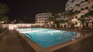 Una piscina al aire libre, sombrillas, tumbonas