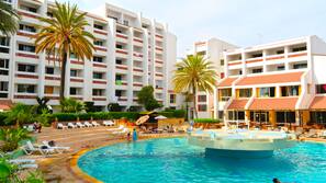 Una piscina al aire libre, sombrillas, tumbonas