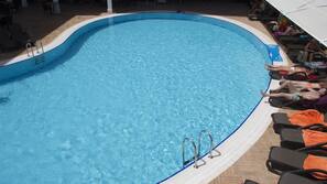 Una piscina al aire libre, sombrillas, tumbonas