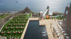 Una piscina al aire libre, sombrillas, tumbonas