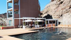 Una piscina al aire libre, sombrillas, tumbonas