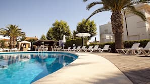 Una piscina al aire libre, sombrillas, tumbonas