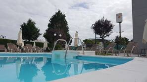 Una piscina al aire libre de temporada, sombrillas, tumbonas