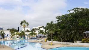 Una piscina al aire libre, sombrillas, tumbonas